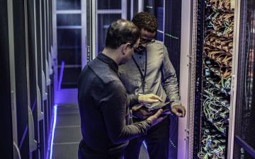 Two men looking at a tablet in a server room